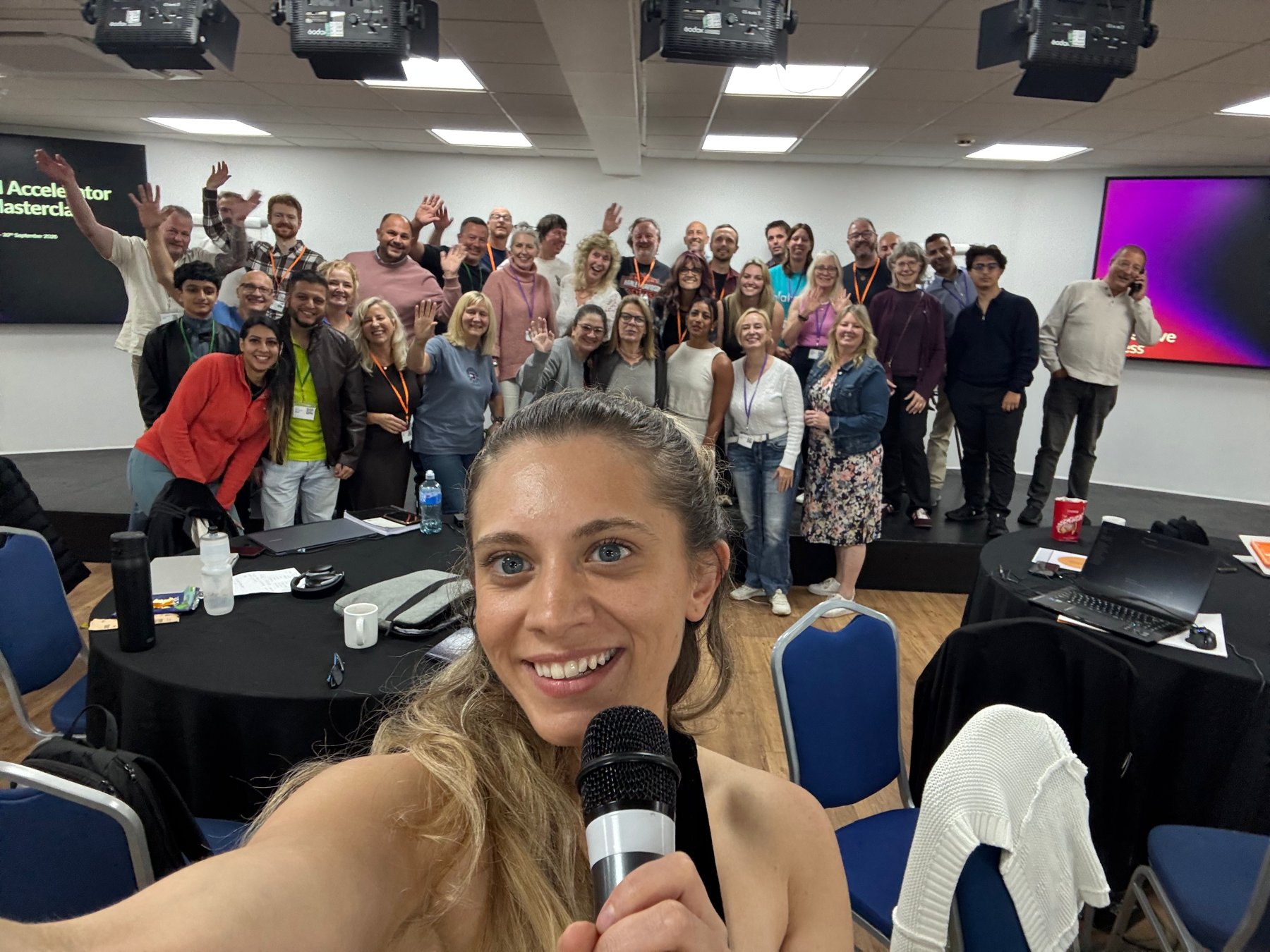 Sabrina on the mic in front of a full room, October 2026